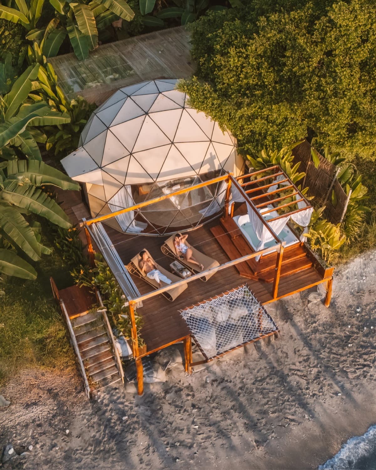Aerial view of Gamat Bay Resort beachfront dome villas surrounded by tropical jungle on Nusa Penida, Indonesia
